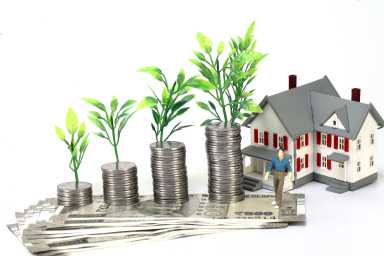 Stack of coins and model home-Concept of wealth creation