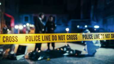 Close Up on Crime Scene Yellow Tape Showing Text Police Line Do Not Cross. Restricted Area to the Public. Police on Duty in the Background. Cinematic Bokeh Effect With Red and Blue Neon Lights