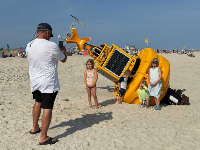 A large yellow buoy that floated ashore in Atlantique over the weekend of August 9 has become the most photographed backdrop for beachgoers. Measuring about 14 feet by 6 feet, the bright buoy lay stranded along the high-water line, partially buried in sand.